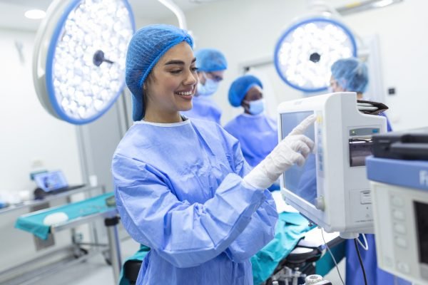 Anesthesiologist keeping track of vital functions of the body during cardiac surgery. Surgeon looking at medical monitor during surgery. Doctor checking monitor for patient health status.